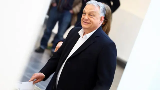 Hungarian Prime Minister Viktor Orbán places his vote in a ballot box during the general election in Budapest, Hungary, 12 April 2026. He is wearing a black blazer and a white shirt.