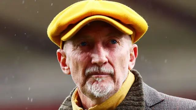 Ian Holloway wearing a yellow flat cap