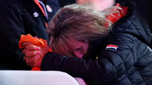 A woman clasps her hand together and bows her head following the partial results of the Hungarian parliamentary election