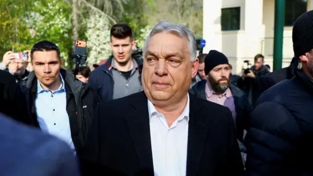 Hungarian Prime Minister Viktor Orban leaves after voting during the Hungarian parliamentary election in Budapest, Hungary, on 12 April 2026. He is wearing a white shirt and black blazer and is accompanied by several colleagues..
