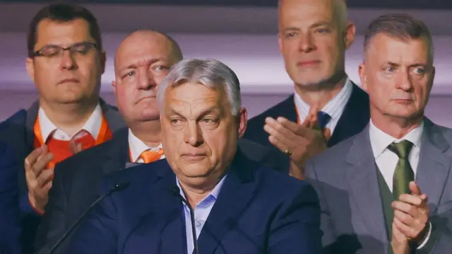 Viktor Orbán looks on as he addresses supporters after the announcement of the partial results of parliamentary election. He is wearing a navy blazer and blue shirt