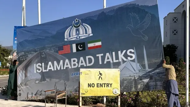 Crews work to take down a sign that marked the historic peace talks between the US and Iran in Pakistan