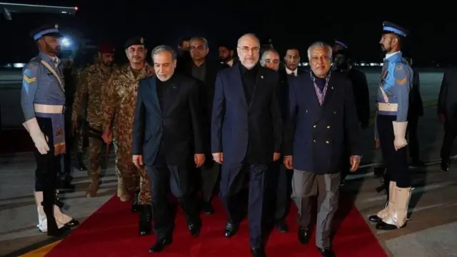 Iranian Parliament Speaker Mohammad Bagher Ghalibaf (C) and Iranian Foreign Minister Abbas Araghchi (L) arrive at the airport in Islamabad alongside other delegates. They are flanked by soldier on a red carpet