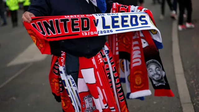 Seller holds a half and half Man Utd and Leeds scarf