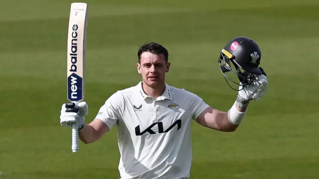 Jamie Smith raises his bat after getting a century for Surrey against Leics