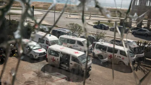 Damaged Lebanese Red Cross vehicles, seen through a broken glass window, after a drone strike damaged vehicles and a building, slightly injuring three workers, in Tyre, Lebanon, April 13, 2026