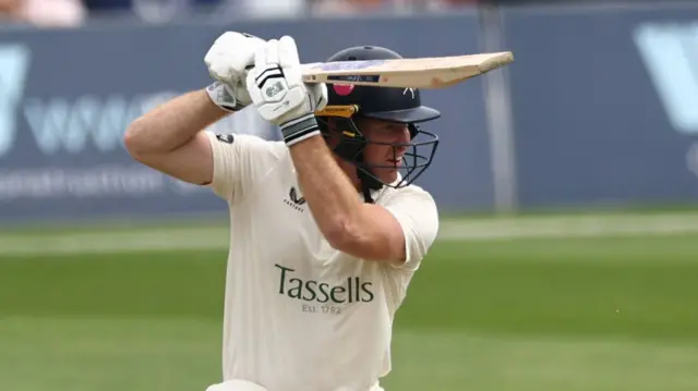 Ben Compton watching intently with a big back lift after hitting the ball