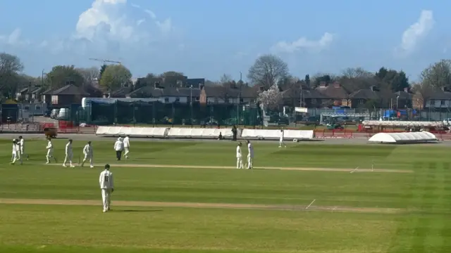 A view from side-on at Old Trafford Cricket Ground with the players, batters and umpires all in shot