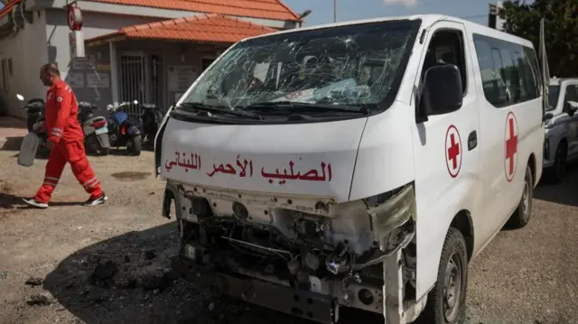 A staff member walks past a damaged Lebanese Red Cross vehicle after a drone strike damaged vehicles and a building, slightly injuring three workers, in Tyre, Lebanon, April 13, 2026.