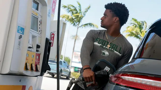 A man watches the price meter as he fills his vehicle at a petrol station