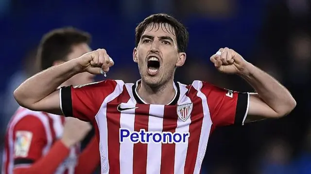Iraola, wearing a red and white striped Athletic Bilbao shirt, punches his arms in the air and roars in celebration