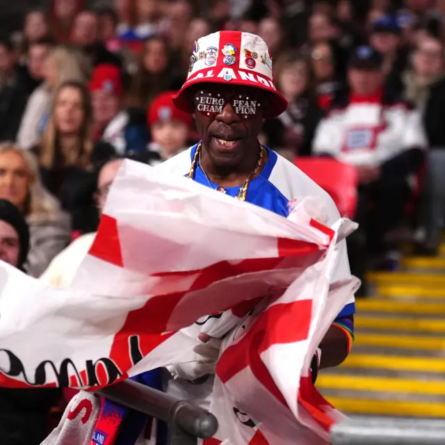 Basil waves England flags in the stands
