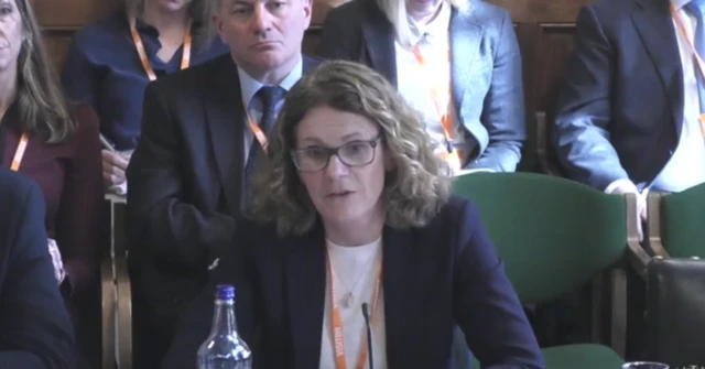 A woman with glasses and long, wavy hair.