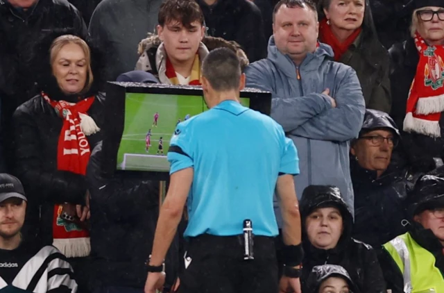 Referee Laurent Bonadei looks at a VAR screen