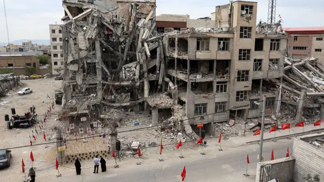 Iranians look at portraits of victims reportedly killed in a US-Israeli airstrike on the residential building near which they are displayed, in Tehran on April 13, 2026.