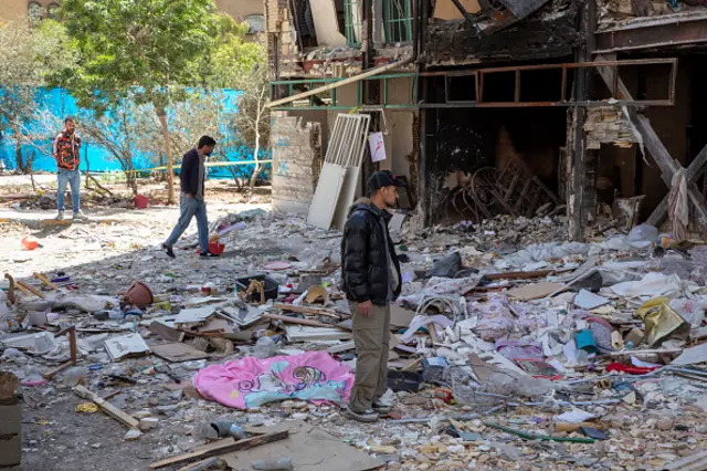 People view debris from a damaged residential building that, according to Iranian authorities, was hit by a strike on
