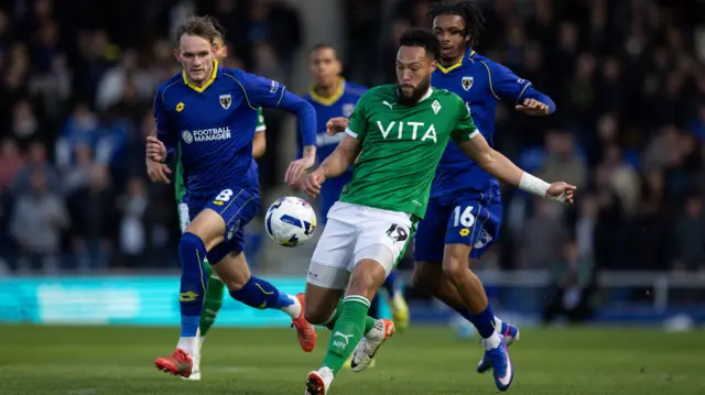 Kyle Wootton, of Stockport County, is chased by Wimbledon's Callum Maycock and Antwoine Hackford