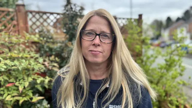 Kerry Clarkson looks to camera for her picture to be taken. She is standing outside in a suburban area