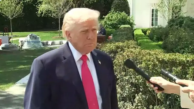 Trump standing outside with reporters holding microphones in front of him