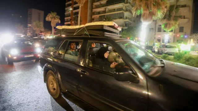 Displaced people return to their homes in a vehicle carrying belongings on its roof