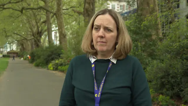 Jenny Ward has blonde hair to her shoulders and wears a dark green top