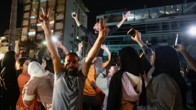 a crowd of people celebrating, with their arms up, in the street
