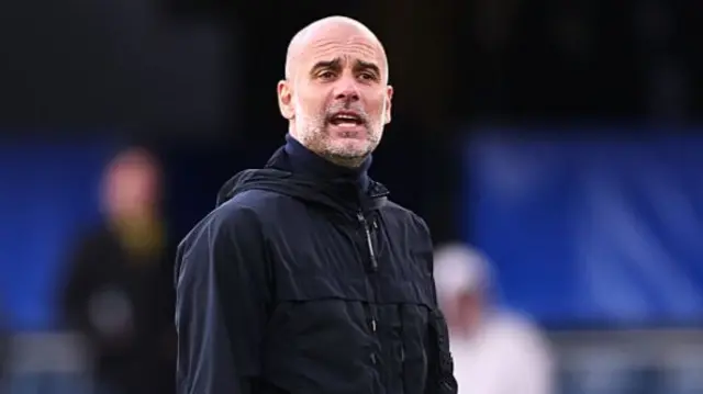 Pep Guardiola dressed in a full black outfit shouting from the line