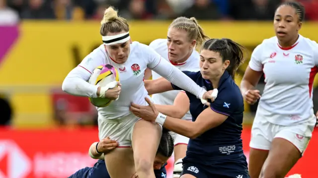 Meg Jones carries the ball for England with two Scotland players attempting to tackle her