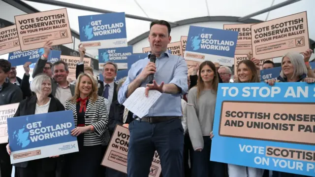 Russell Findlay backed by Tory supporters holding banners urging voters to back them on the pink ballot paper