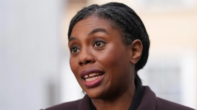 Head shot of Badenoch who speaks. The background is blurry but a light colour