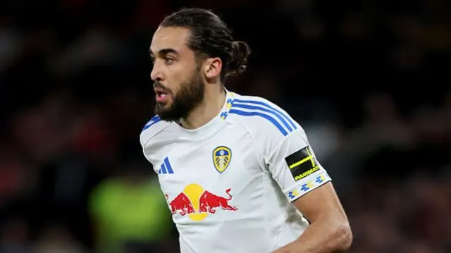 He is wearing a white jersey with the Red Bull logo at the front