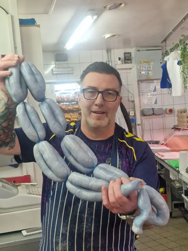 A butcher with blue sausages