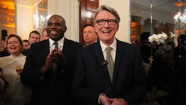 Mandelson stands next to David Lammy in a crowded room