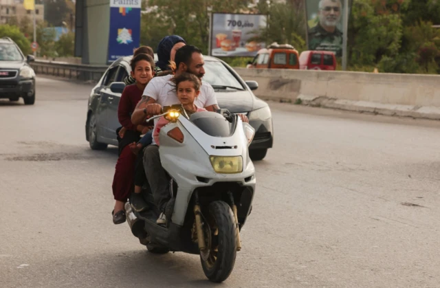 Five people cram onto a motorbike as it zips along a highway towards Sidon
