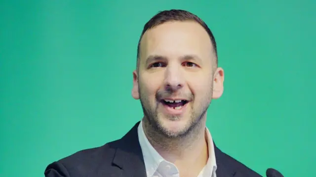 Head shot of Polanski who speaks in front of a plain green background