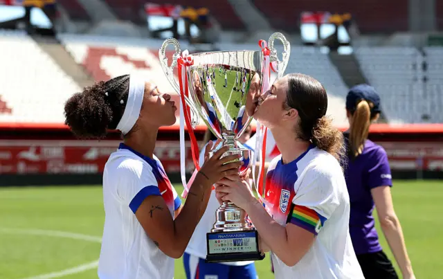 Gunning-Williams and Mace kiss the trophy before lifting it into the air