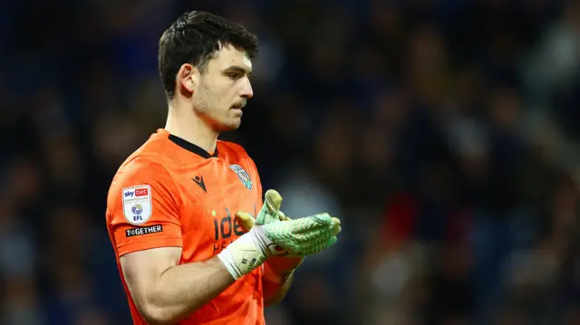 A photo of Max O'Leary in his orange West Bromwich Albion goalkeeping kit softly applauding