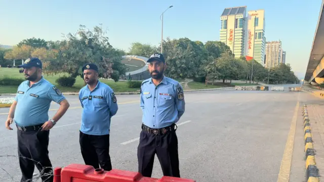 Τρεις άνδρες με στολή στέκονται κλείνοντας μέρος ενός δρόμου