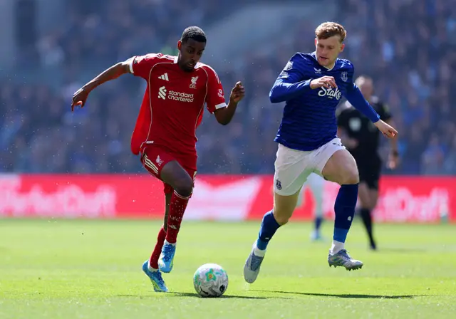Alexander Isak of Liverpool runs with the ball under pressure from Jarrad Branthwaite of Everton