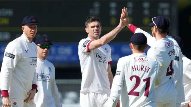 James Anderson takes the congratulations of his Lancashire team-mates after taking a wicket.