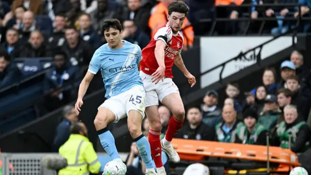 Abdukodir Khusanov of Manchester City is challenged by Declan Rice of Arsenal