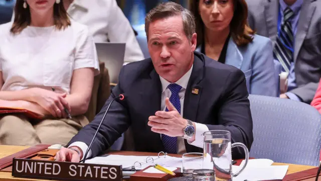 Mike Waltz at a table in a dark suit with a 'United States' board in front of him