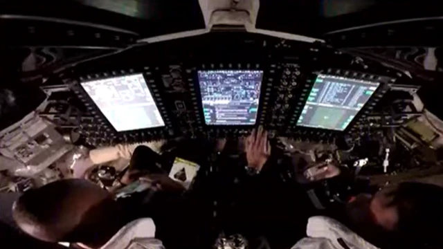 Astronauts monitor screens inside the Orion capsule