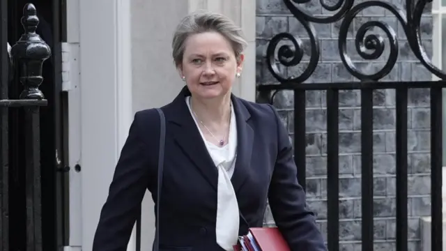 UK Foreign Secretary Yvette Cooper leaving Downing Street in a suit holding red folders.