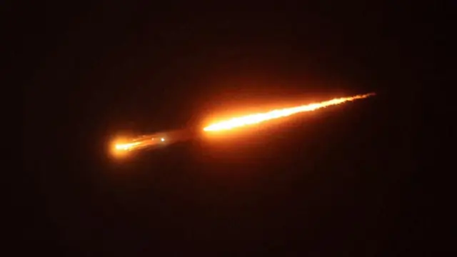 two bright red missiles crossing through the night sky