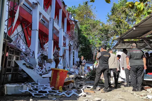 Police officers inspect the damage at the National Sports Committee building in Manado
