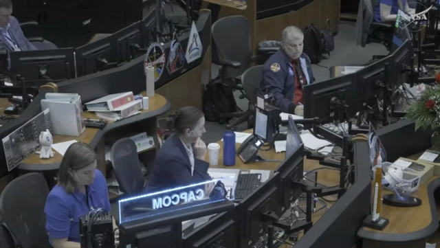 Three staff members at Nasa sat at desks, wearing headsets