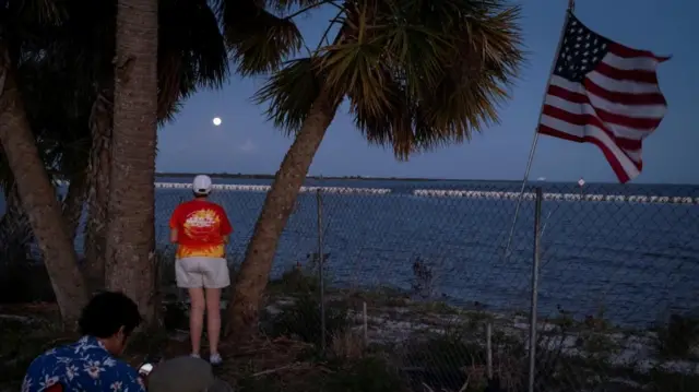 A spectator at the Kennedy Space Center looks at the moon after the Artemis II launch
