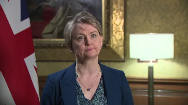 Yvette Cooper sits next to a Union Flag as she is interviewed for a pool clip