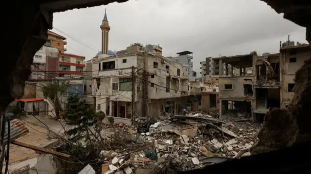 damaged buildings surround collapsed building of rubble